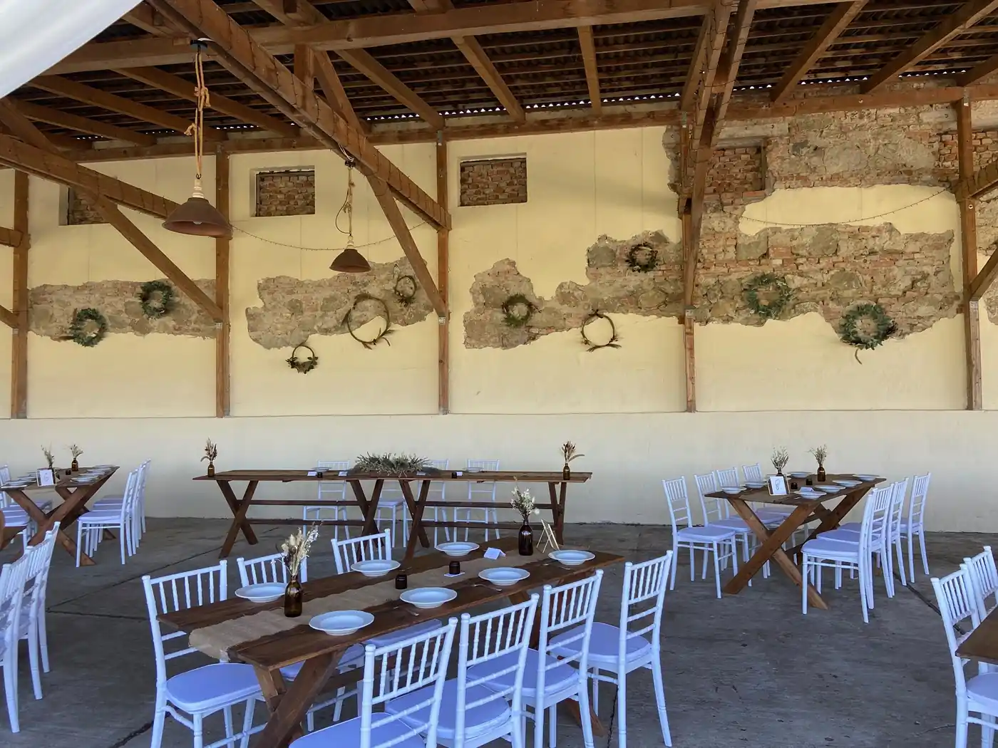 Rusztikus kialakítású pajta, ideális vidéki esküvői helyszín asztalokkal és székekkel.